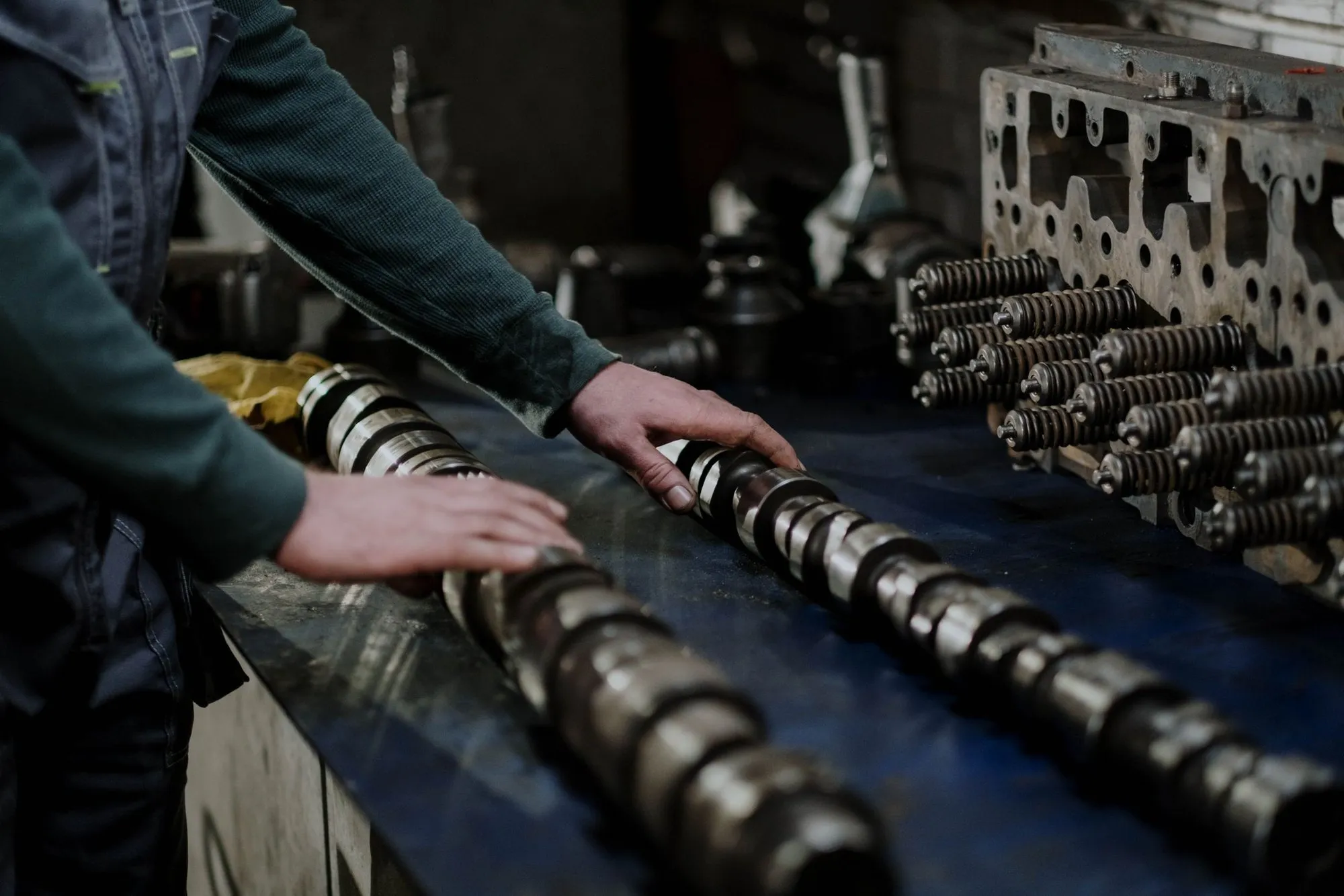 A technician handling camshafts in a parts workshop