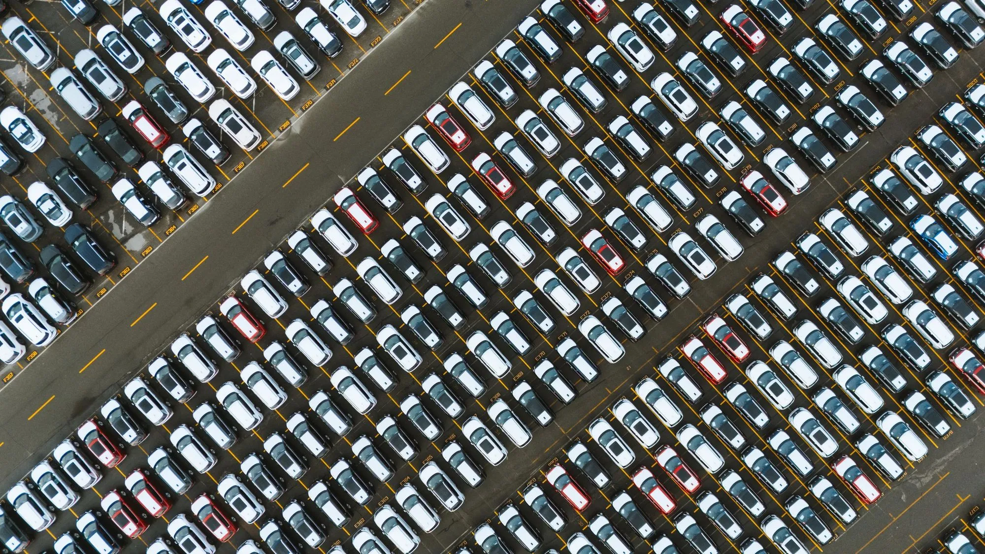 Aerial view of new vehicles parked in rows at a distribution compound